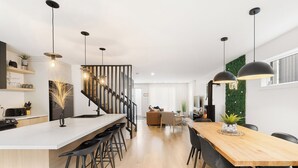 Una cocina moderna con una isla central, taburetes negros y luminarias colgantes.