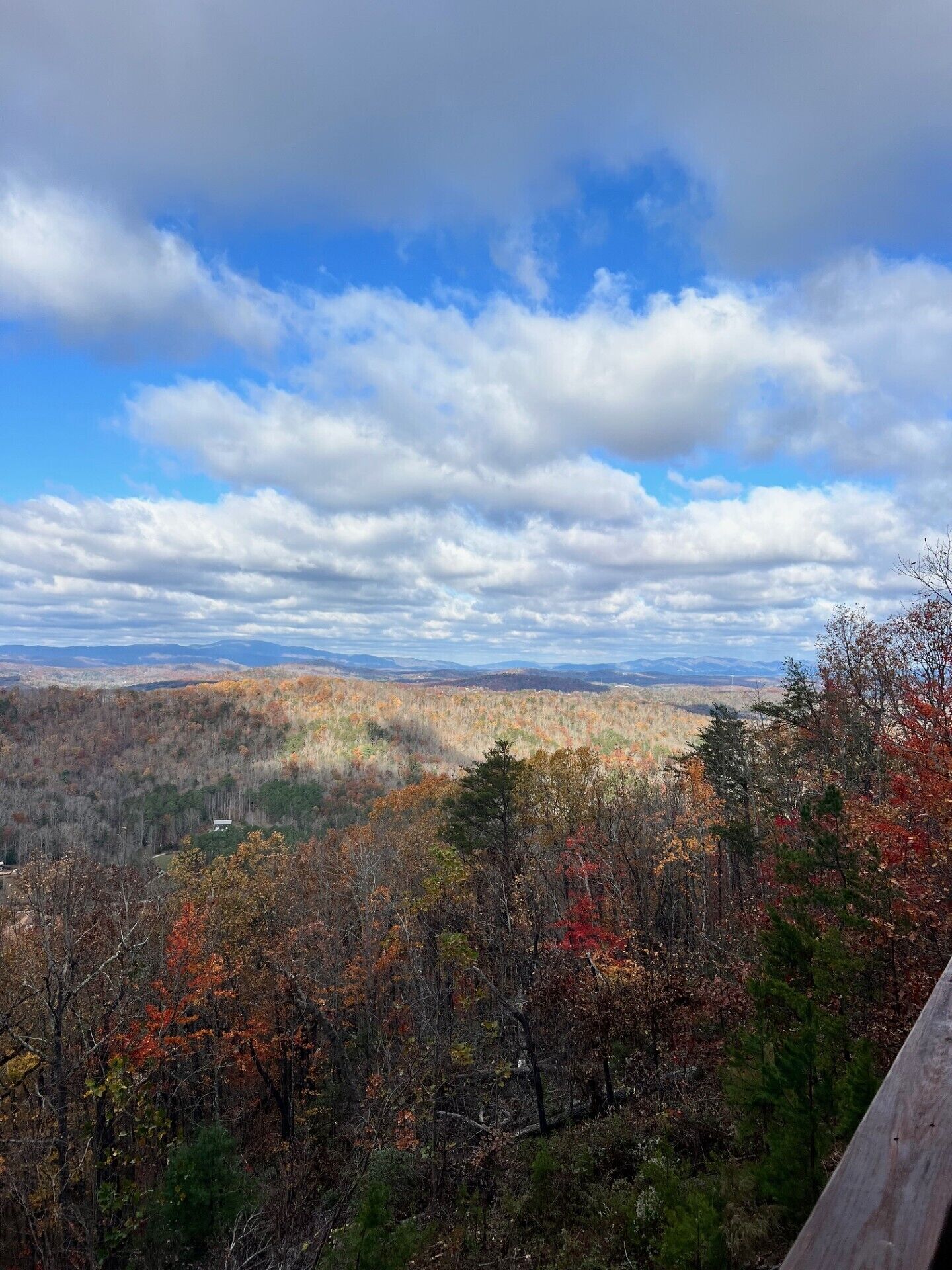 A panoramic view of a mountainous landscape with autumn foliage and a partly cloudy sky.