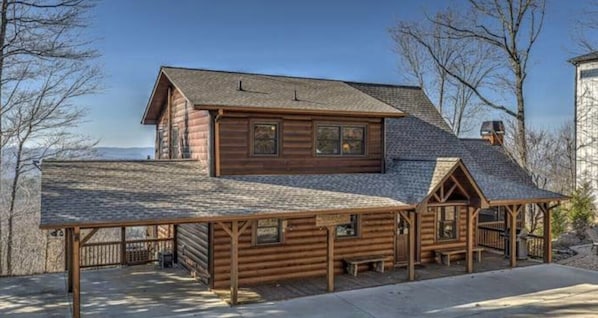 A log cabin with a covered porch and a small attached structure.