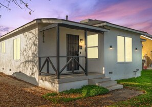 Une maison moderne de plain-pied, dotée d’un porche couvert, d’une porte d’entrée et d’un petit jardin à l’avant.