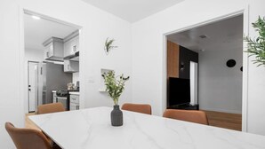 Un espace repas moderne avec une table en marbre, des chaises marron et un vase de fleurs.