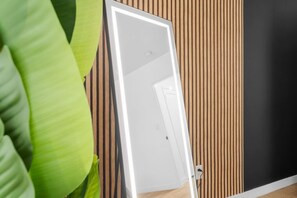 Une pièce avec un mur recouvert de lambris en bois, une porte blanche et une plante verte.