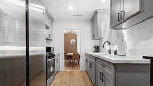 Une cuisine moderne dotée d’appareils électroménagers en acier inoxydable, de meubles de rangement gris et d’une table à manger en bois avec des chaises.