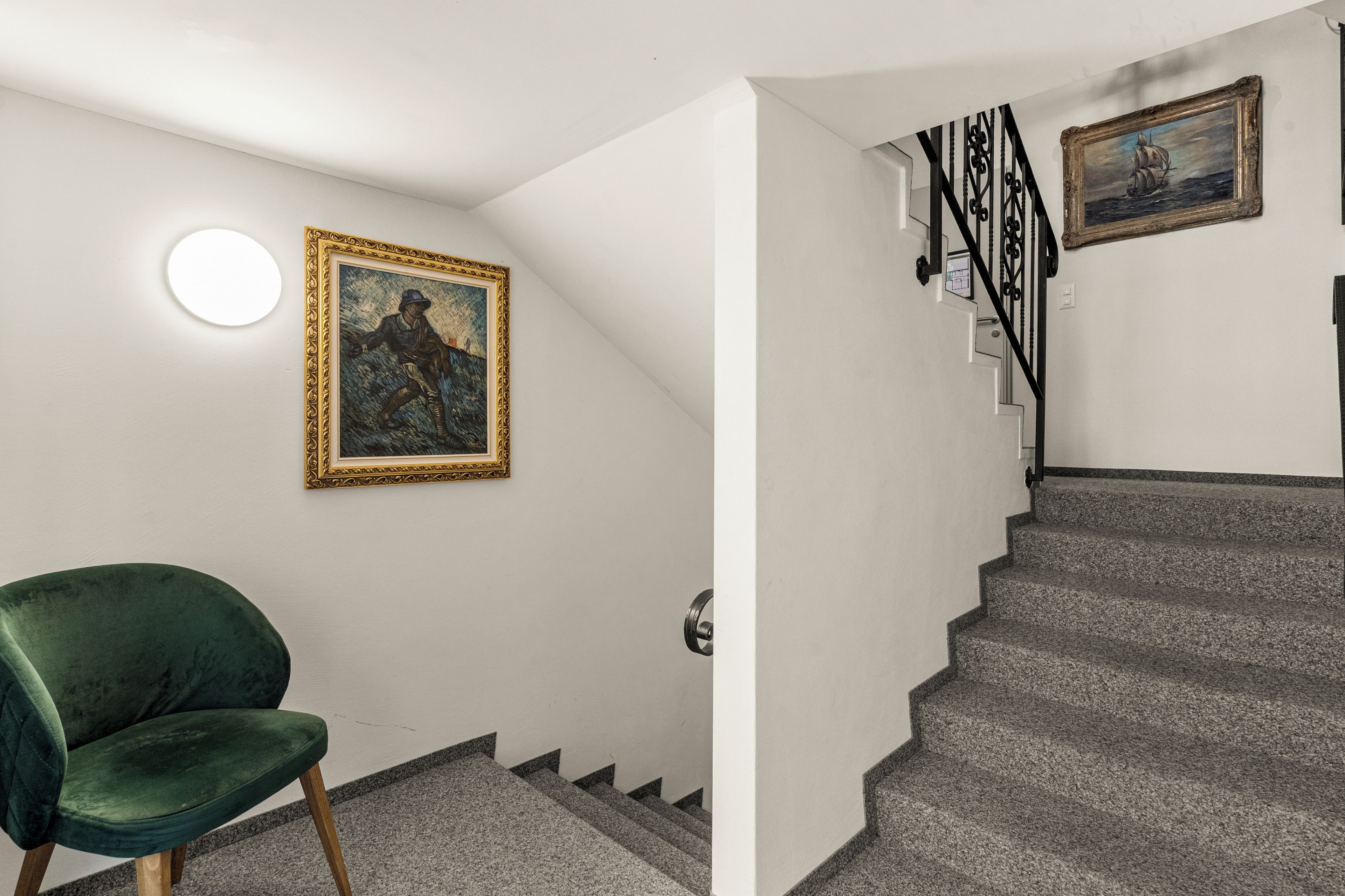 Un escalier avec une rampe noire et un tableau accroché au-dessus.