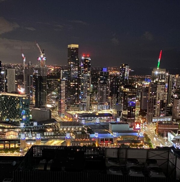 A nighttime cityscape with illuminated skyscrapers and a busy street.