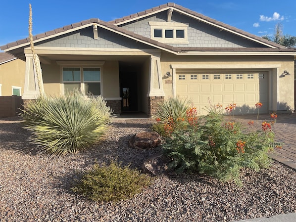 A residential house with a garage, a driveway, and landscaping.