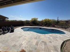 A swimming pool with a curved edge, surrounded by a paved patio.