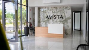 Een receptiebalie met de naam 'AVISTA' op een marmeren wand, een glazen deur en een schone, betegelde vloer.