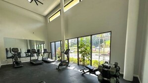 Een sportschool met trainingsapparatuur, grote ramen en uitzicht op de omgeving.