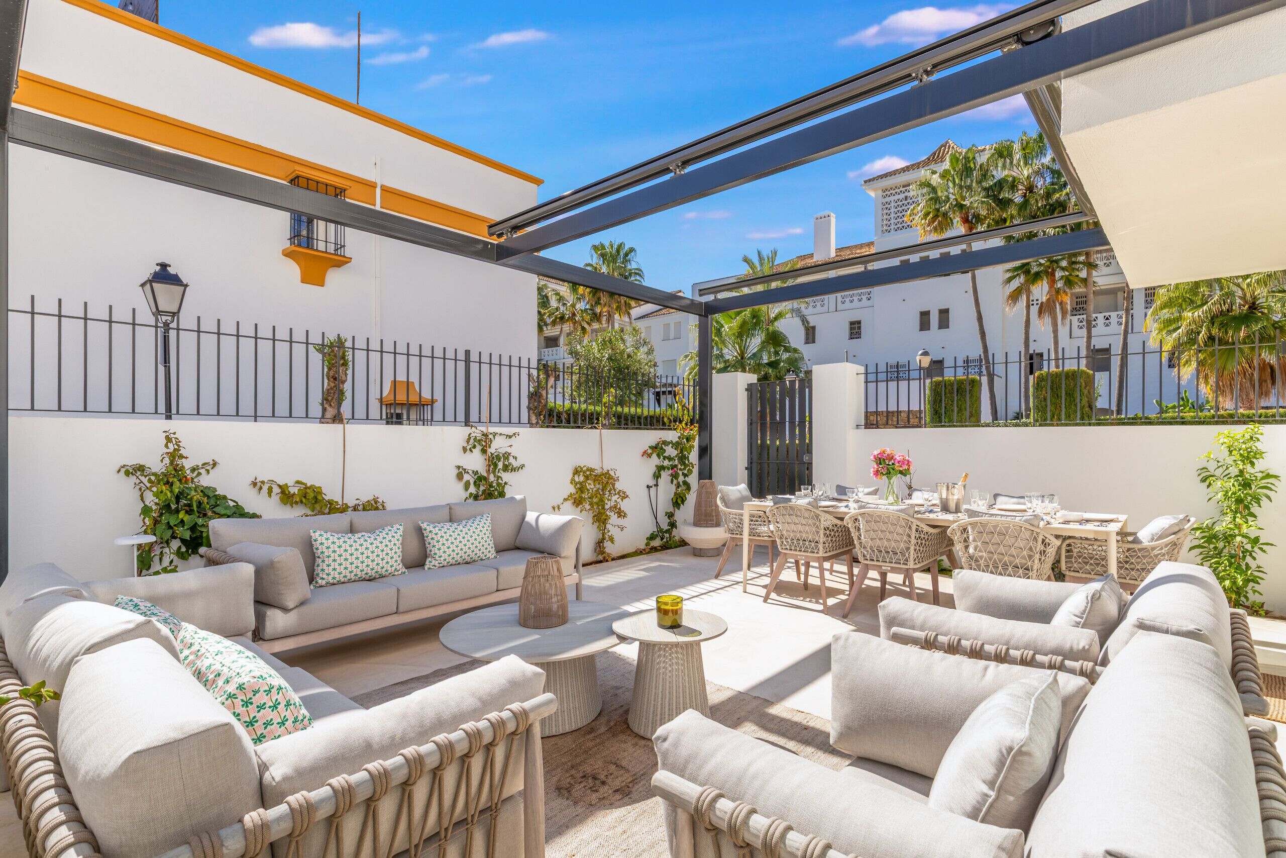 Eine sonnendurchflutete Terrassenanlage mit einer Couch, Stühlen und einem Esstisch.