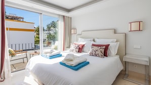 Une chambre d’hôtel avec un grand lit, un balcon et une vue sur les palmiers.