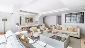 Un vaste espace de vie au design moderne, comprenant un ensemble de canapés, une table basse et un coin repas avec des chaises et une table.