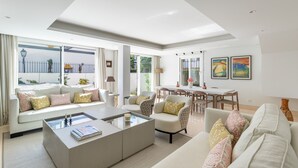 Un salon moderne comprenant un canapé, des fauteuils, une table basse et un coin repas avec une table et des chaises.
