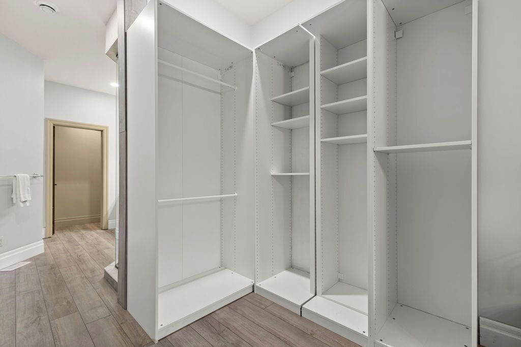 Un dressing accessible sans porte, doté d’étagères ouvertes et d’une porte de placard miroir.