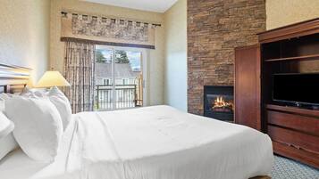 Une chambre d’hôtel avec un lit, une télévision, une cheminée et un balcon avec des rideaux.