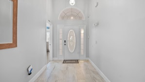 A hallway with a white door, a light fixture, and a doormat.