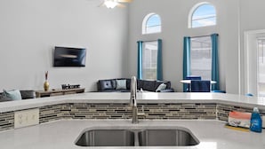 A modern kitchen with a stone backsplash, a built-in sink, and a ceiling fan.