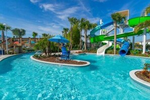 Un área de piscina con tobogán y sillones de descanso.
