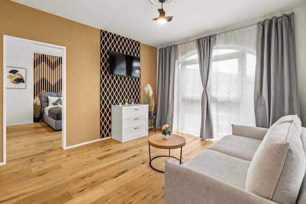 A modern living room with a sofa, a coffee table, a TV, and a decorative wall panel.