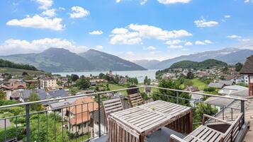 A balcony with a view of a lake, mountains, and a village.
