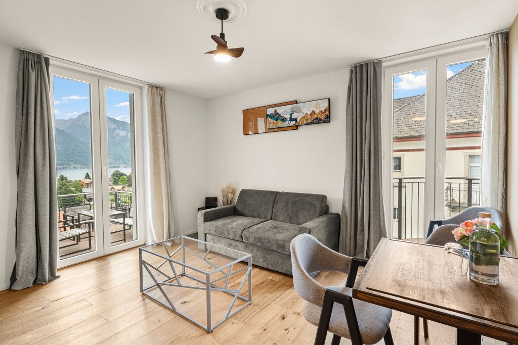 Una habitación con sofá, una mesa de comedor y vistas a montañas a través de amplios ventanales.