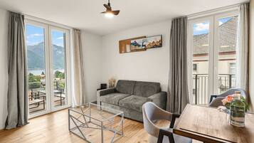Una habitación con sofá, una mesa de comedor y vistas a montañas a través de amplios ventanales.