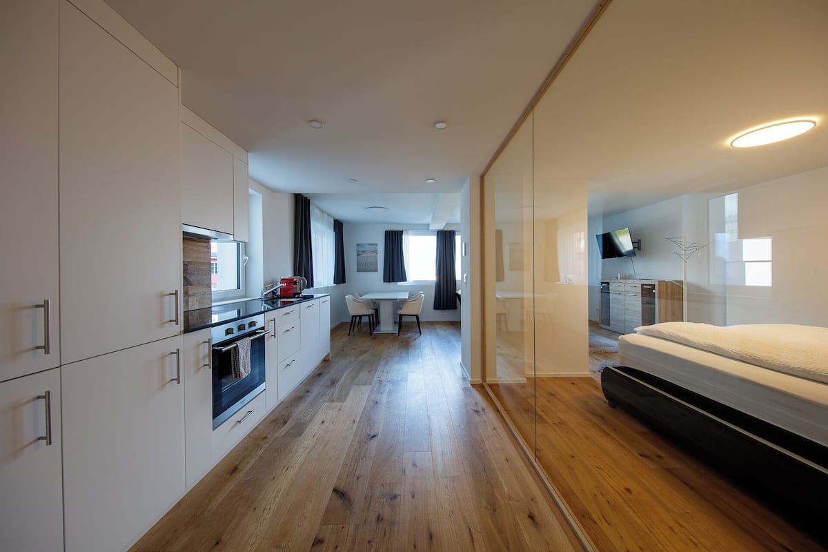A modern apartment with a kitchen, dining area, and a bedroom.