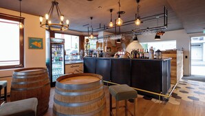 A bar area with wooden barrels, a minibar, and a variety of bottles. - BERG&BERG APARTMENTS-Spiez Self Check-In (Spiez)