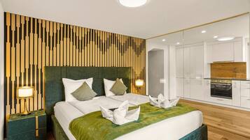 A modern hotel room with a large bed, a wooden accent wall, a kitchenette, and a separate bathroom.