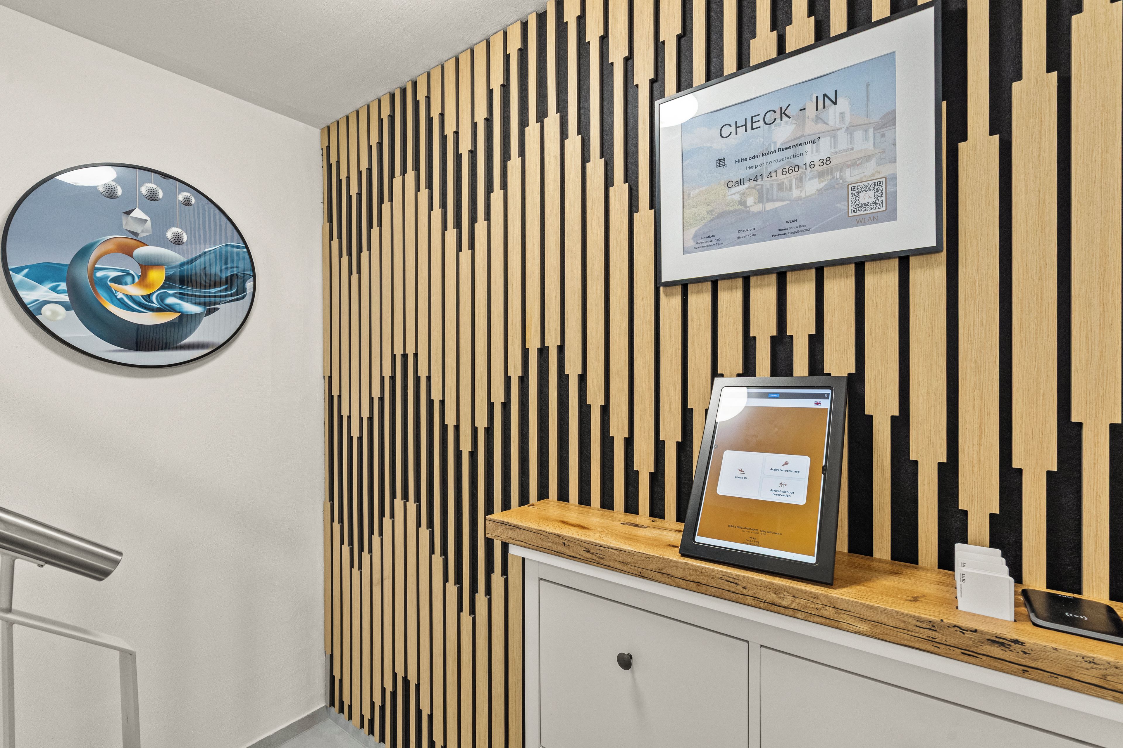 A reception desk with a check-in kiosk, a framed welcome sign, and a circular artwork on the wall.