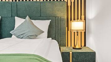A bed with a green upholstered headboard, a bedside table with a lamp, and a wall with vertical wooden slats.