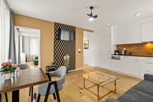 Una sala de estar moderna con comedor, cocina y televisor montado en la pared.