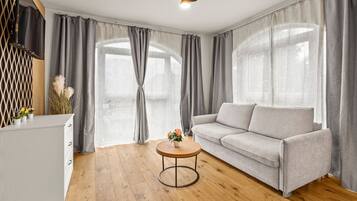 A modern living room with a sofa, a round coffee table, and a TV on a stand.