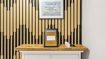 En receptionsdisk med et indrammet 'CHECK-IN' skilt, en tablet og en smartphone på disken.