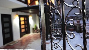 A snow-covered outdoor area with a metal gate and a building entrance. - Guesthouse Bujtina Leon  (Korçë)