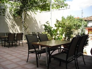 An outdoor patio with a table and chairs, surrounded by greenery and a white wall. - Guesthouse Bujtina Leon  (Korçë)