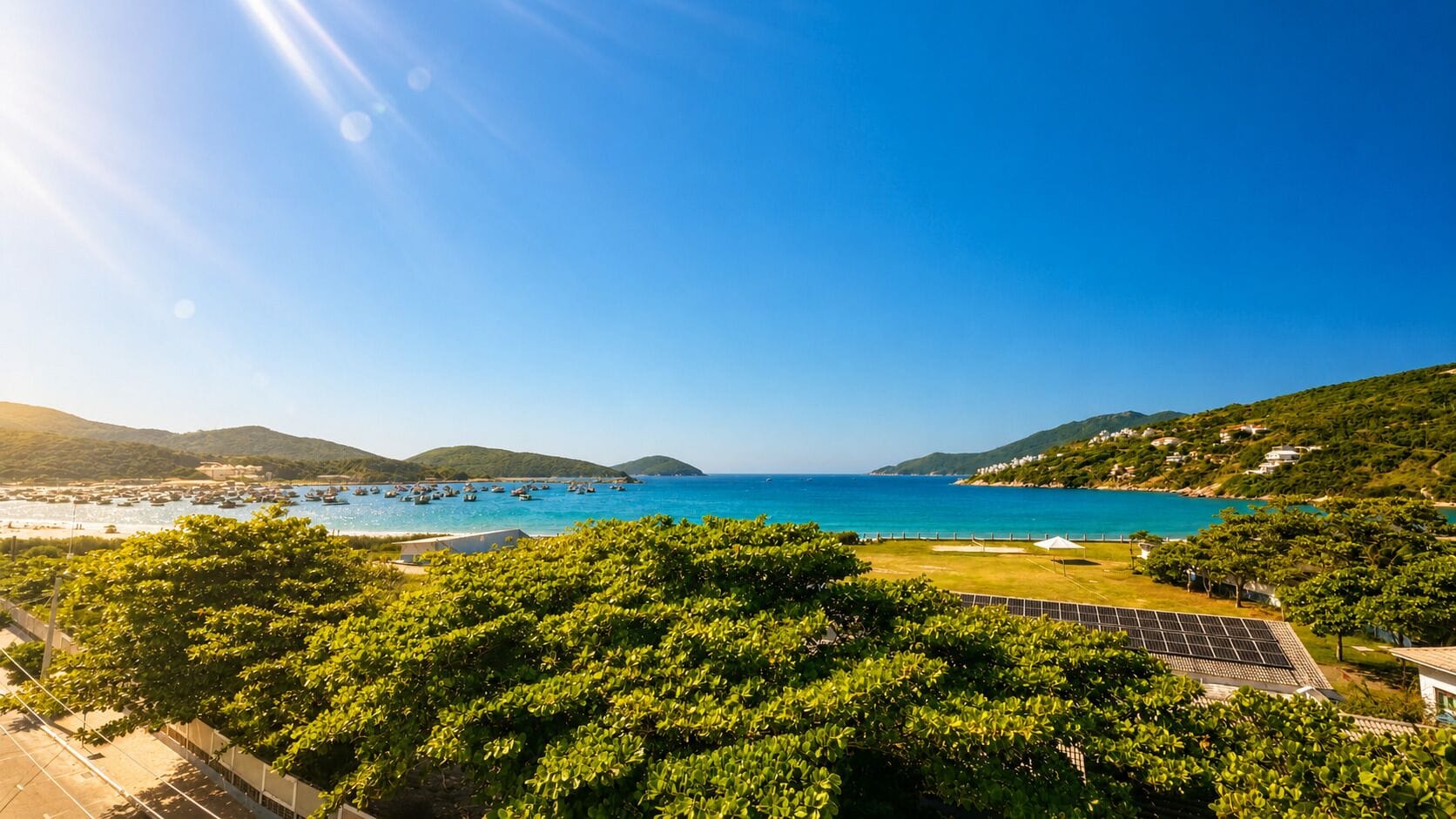 A coastal view with a clear sky, a body of water, and green hills in the background.