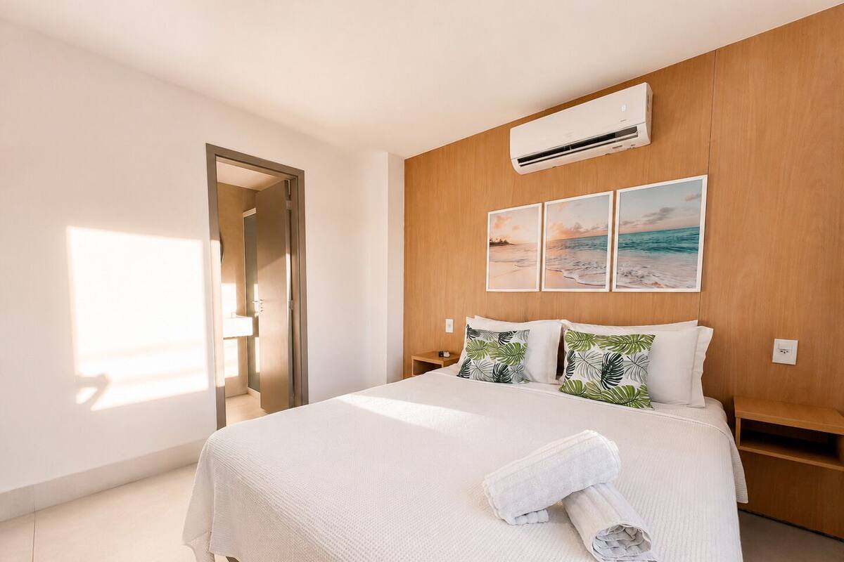 Een slaapkamer met een bed, een nachtkastje, een wandairconditioner en een deur.