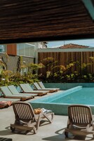 Una piscina al aire libre, sombrillas, sillones reclinables de piscina