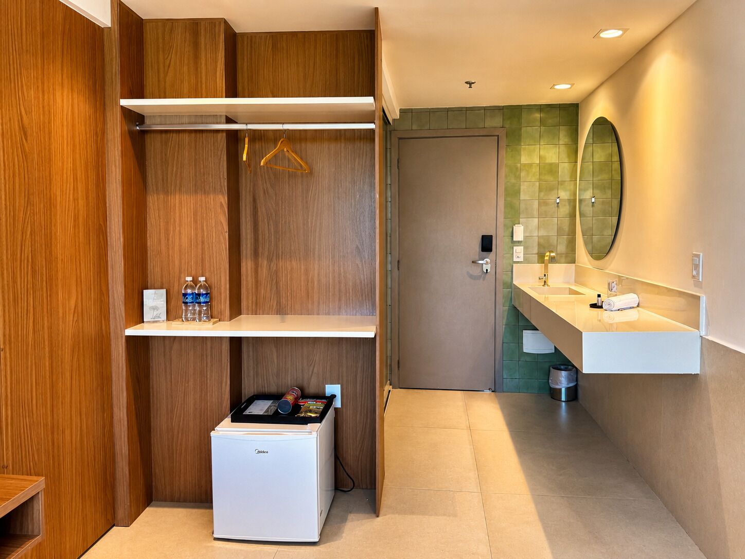 A modern bathroom with a white sink, mirror, and a small refrigerator.