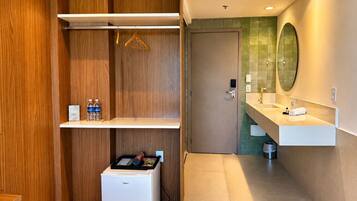 A modern bathroom with a white sink, mirror, and a small refrigerator.