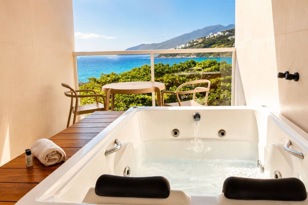 Een hottub met uitzicht op zee, een houten terras en een tafel met stoelen.