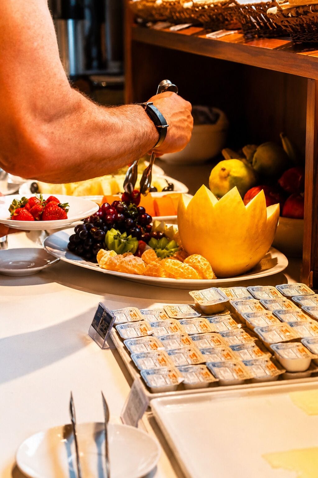 A buffet setup with various food items and a person serving.