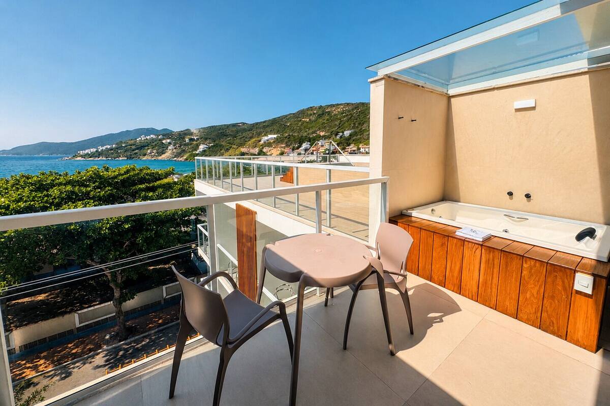 Een balkon met uitzicht op zee, een bubbelbad en twee stoelen.