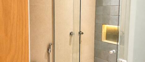 Un baño moderno con ducha de vidrio, inodoro y barra para toallas.