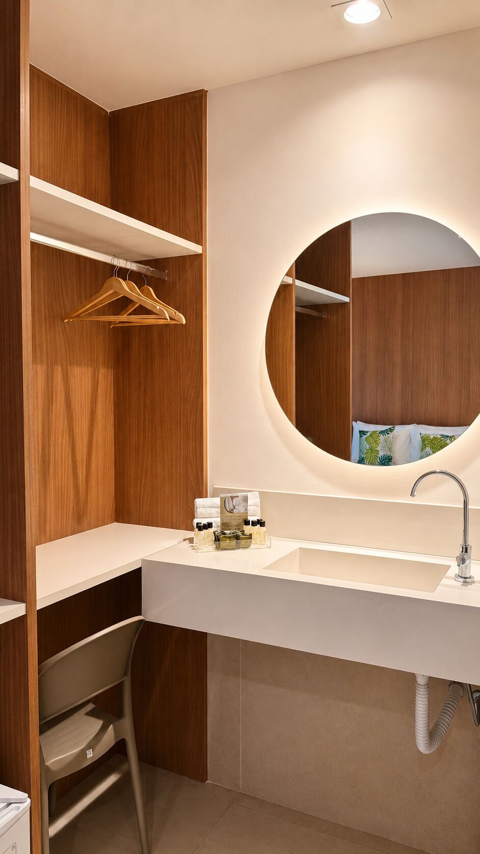 A modern bathroom with a wooden vanity, a round mirror, and a white sink.