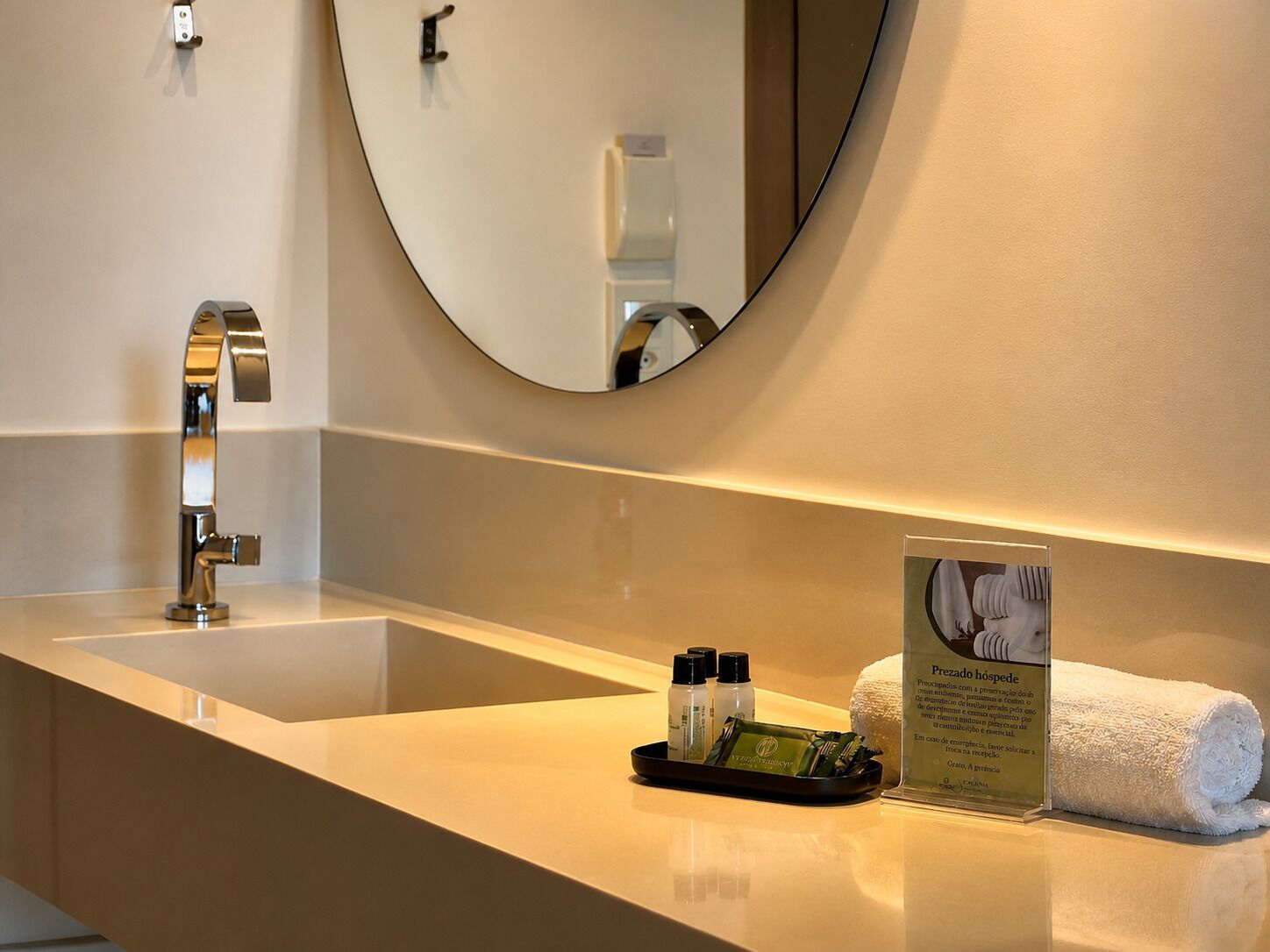 A modern bathroom with a sink, mirror, and toiletries.