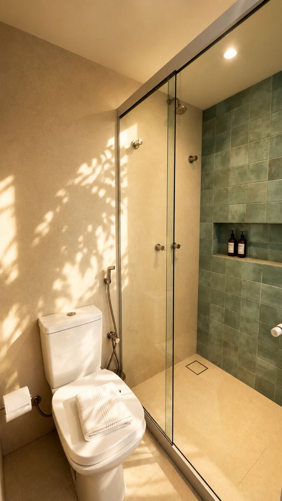 Et moderne badeværelse med en brusekabine i glas, et toilet og en hylde med toiletartikler.