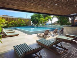 Una piscina al aire libre, sombrillas, tumbonas