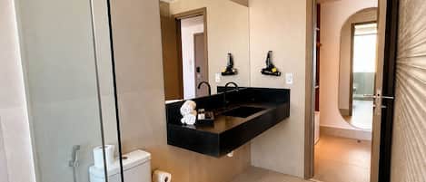 A modern bathroom with a glass shower enclosure, a toilet, a sink with a black countertop, and a mirror above the sink.